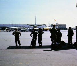 Guys under Caribou wing at Tan Son Nhut staring at an Air France 707. It's going to Paris. We're going to Nha Trang.